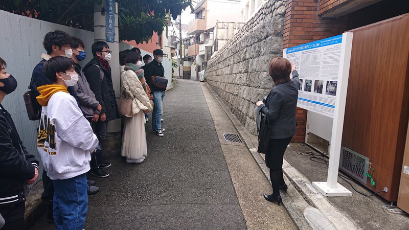 神戸ジューコム跡地の案内板前で説明を受ける学生たち